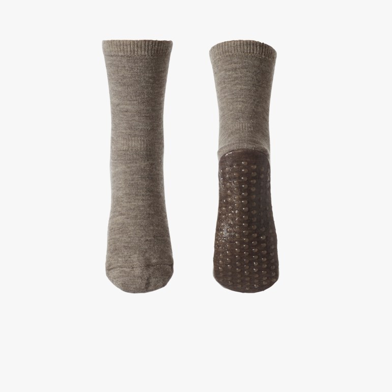 Et par grå antisklisokker, en vist forfra og en som viser sin piggede såle.