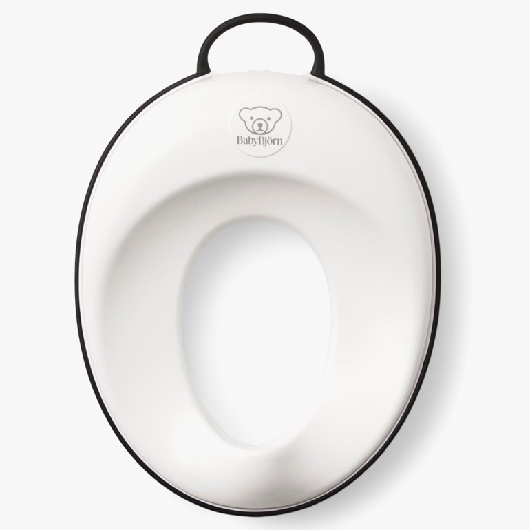 Hvit toalettreningssete for babyer med svart kant og håndtak, ovenfra.