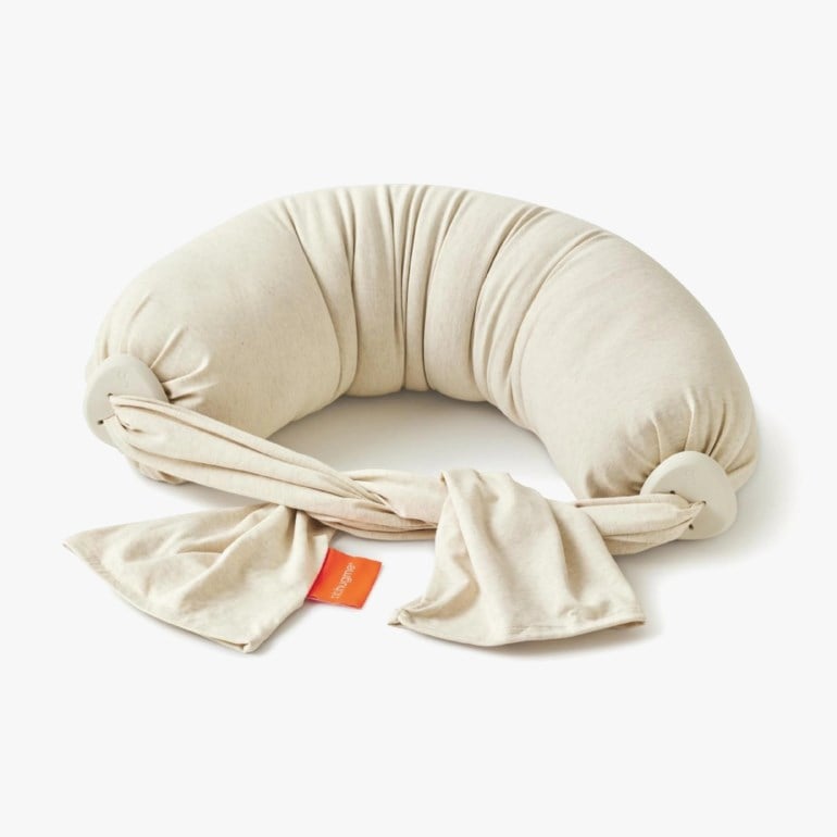 Kremfarget U-formet ammepute med lysegrå ringer som forbinder en tøyrem og en oransje etikett.