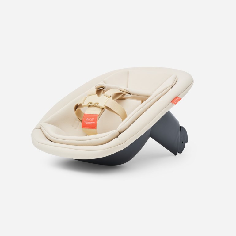 En beige babygyngestol med mørkegrå base, med en lys beige sele med en oransje etikett.