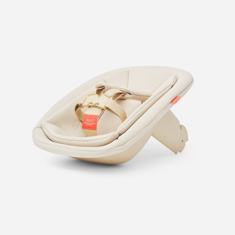 Kremfarget babygynge med polstret innlegg og beige 3-punkts sikkerhetssele med oransje varsellapp.