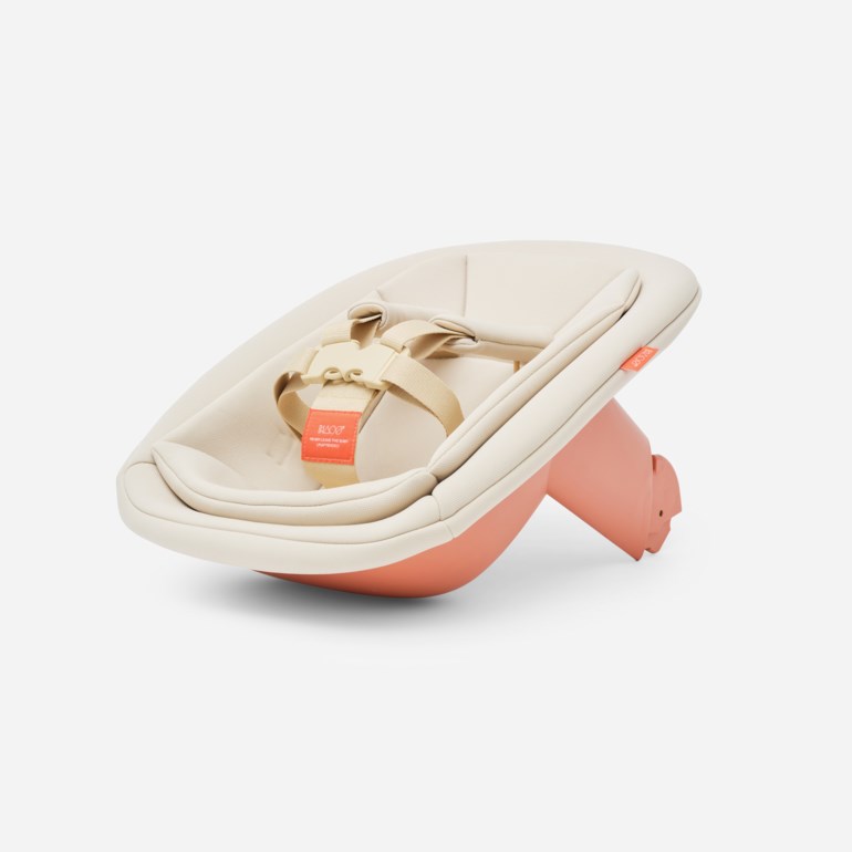 En ergonomisk babyvippestol med korallrosa base og beige stoffsete, med lys sele og spenne.