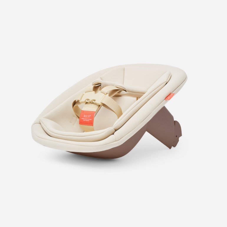 Beige babyvippe med brun base, med lys beige sele med spenne og en oransje etikett.