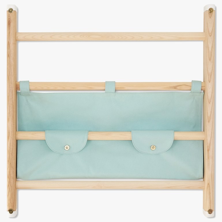 Lys trestigehylle med to lyseblå stofflommer, de nedre lommene har gullfargede knapper.