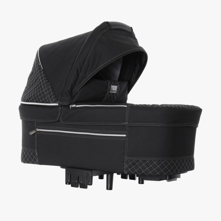 Svart liggedel for baby med quiltede sider, hvite sømmer og matchende kalesje, sett fra siden.