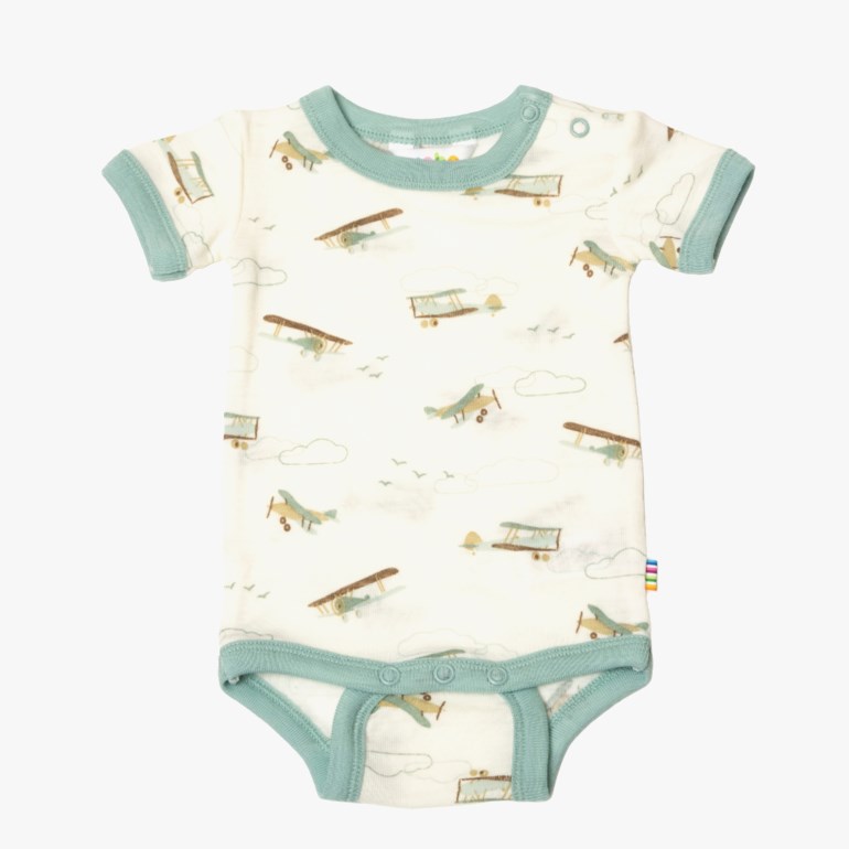 Baby kortermet offwhite body med grønn kant, flymønster og trykknapper, forfra.