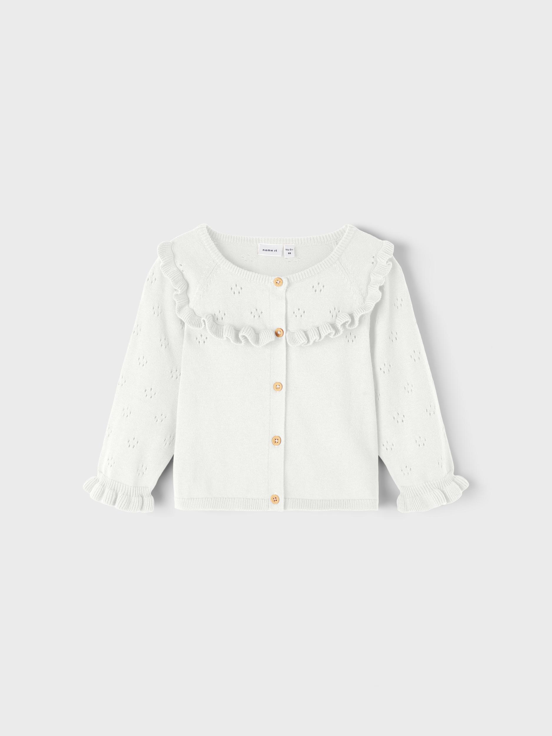 Barns hvit strikket cardigan med rysjekrage og mansjetter, hullmønster og knappelukking foran.