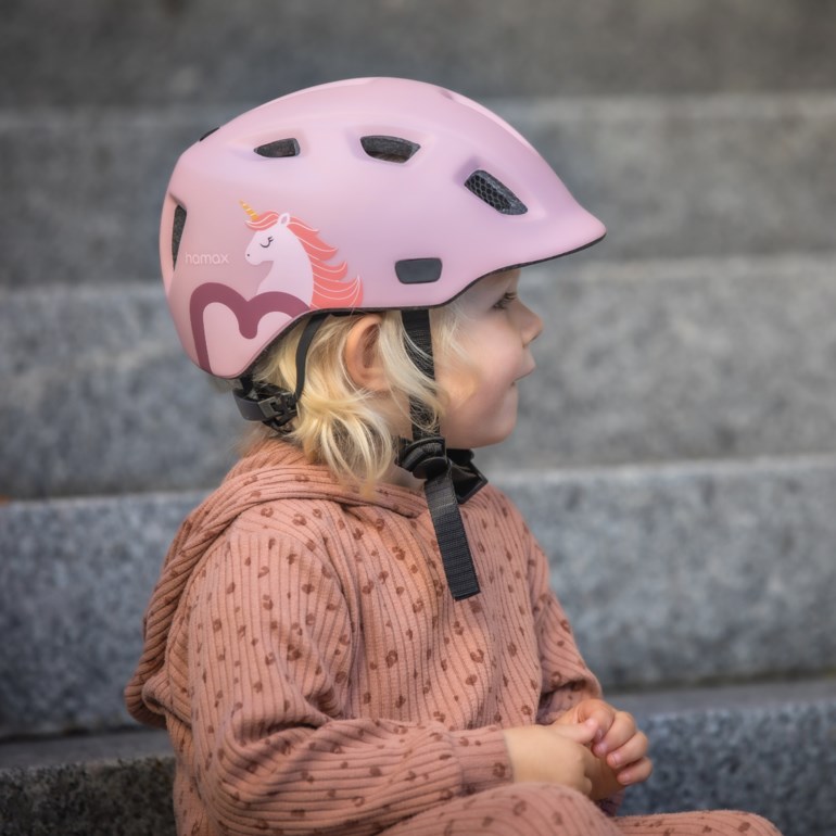Barn med en rosa enhjørningshjelm, iført en rosa ribbet hettegenser og matchende bukser.