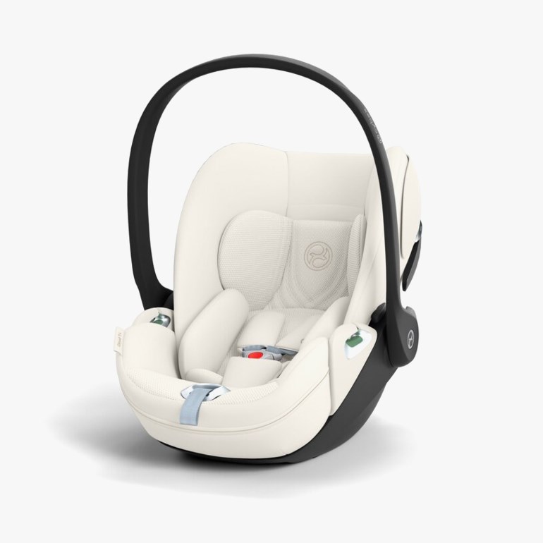 Et kremfarget og svart bilsete for babyer med justerbart håndtak, sikkerhetssele og ergonomisk hodestøtte.