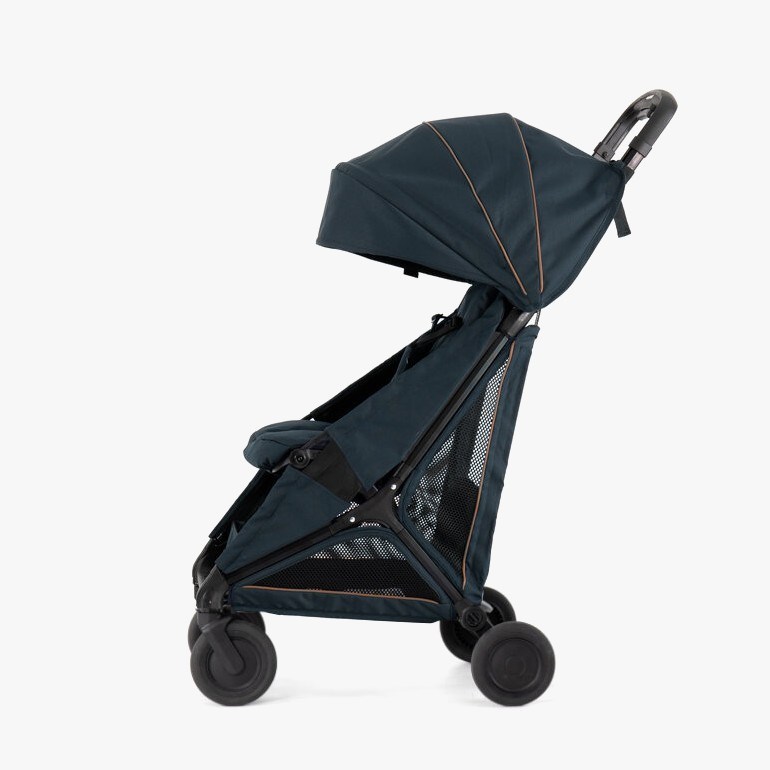 En mørkeblå kompakt barnevogn med solskjerm, nettingpaneler, brun piping og sorte hjul, sett fra siden.