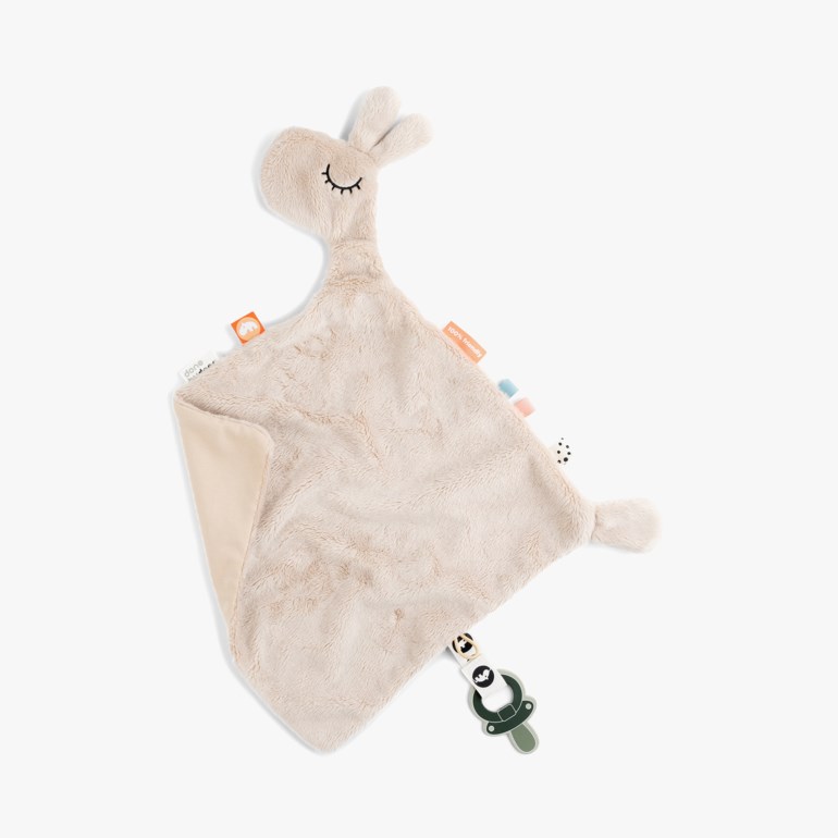 Beige myk koseklut med lama-hode, lukkede øyne, flere merkelapper og en mørkegrønn smokkeholder.