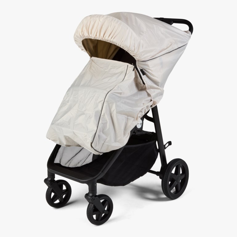 Lys beige tilpasset værdekke på en svart barnevogn, forfra.