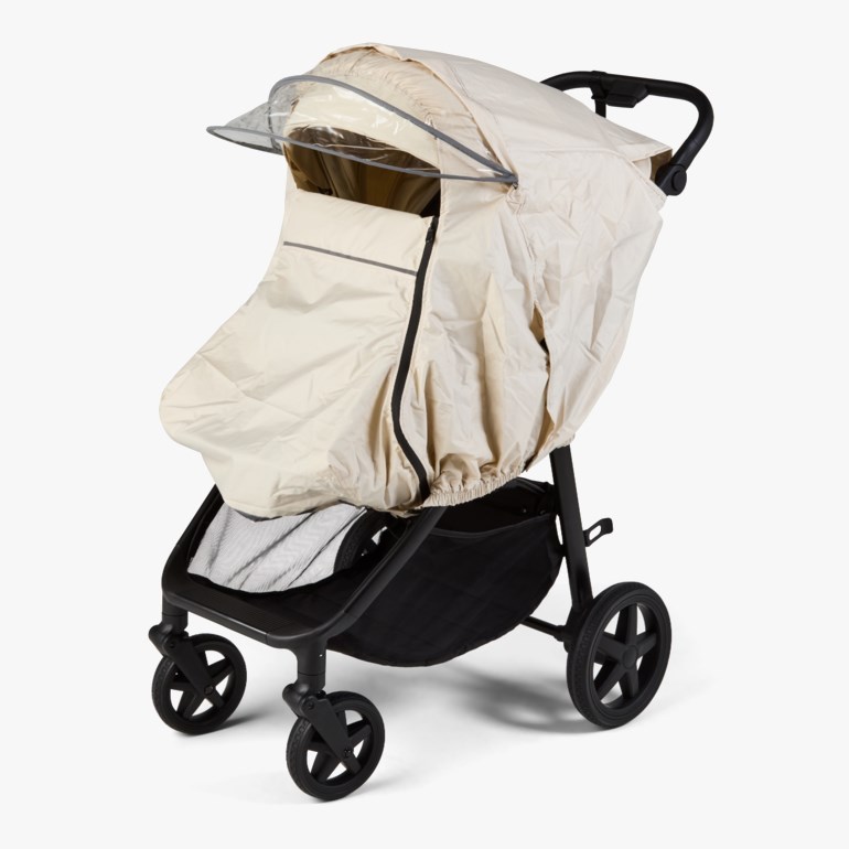Beige vognpose med gjennomsiktig visir og svarte glidelåsdetaljer på en svart barnevogn.