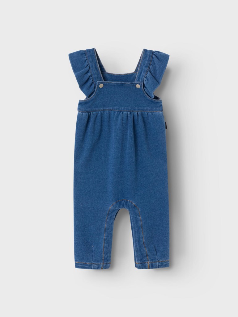 Frontvisning av en blå denim babyoverall med volangkantede skulderstropper og to sølvknapper.