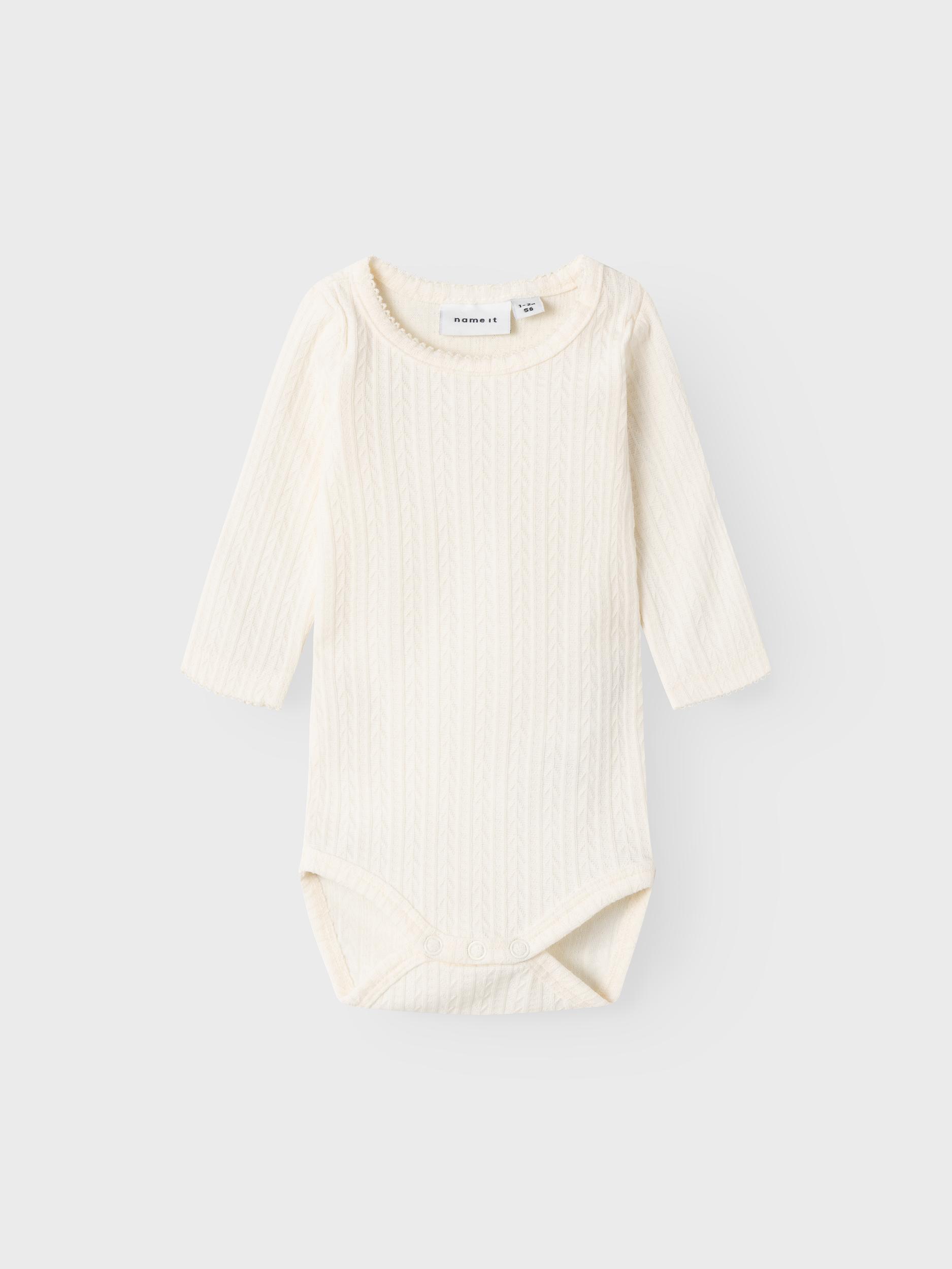 Hvit babybody i teksturert strikket stoff med rund hals og lange ermer.