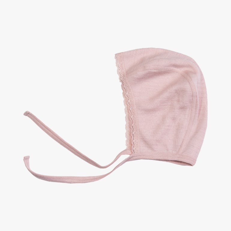 Lys rosa strikket babykyse med blondekant langs ansiktsåpningen og knytebånd.