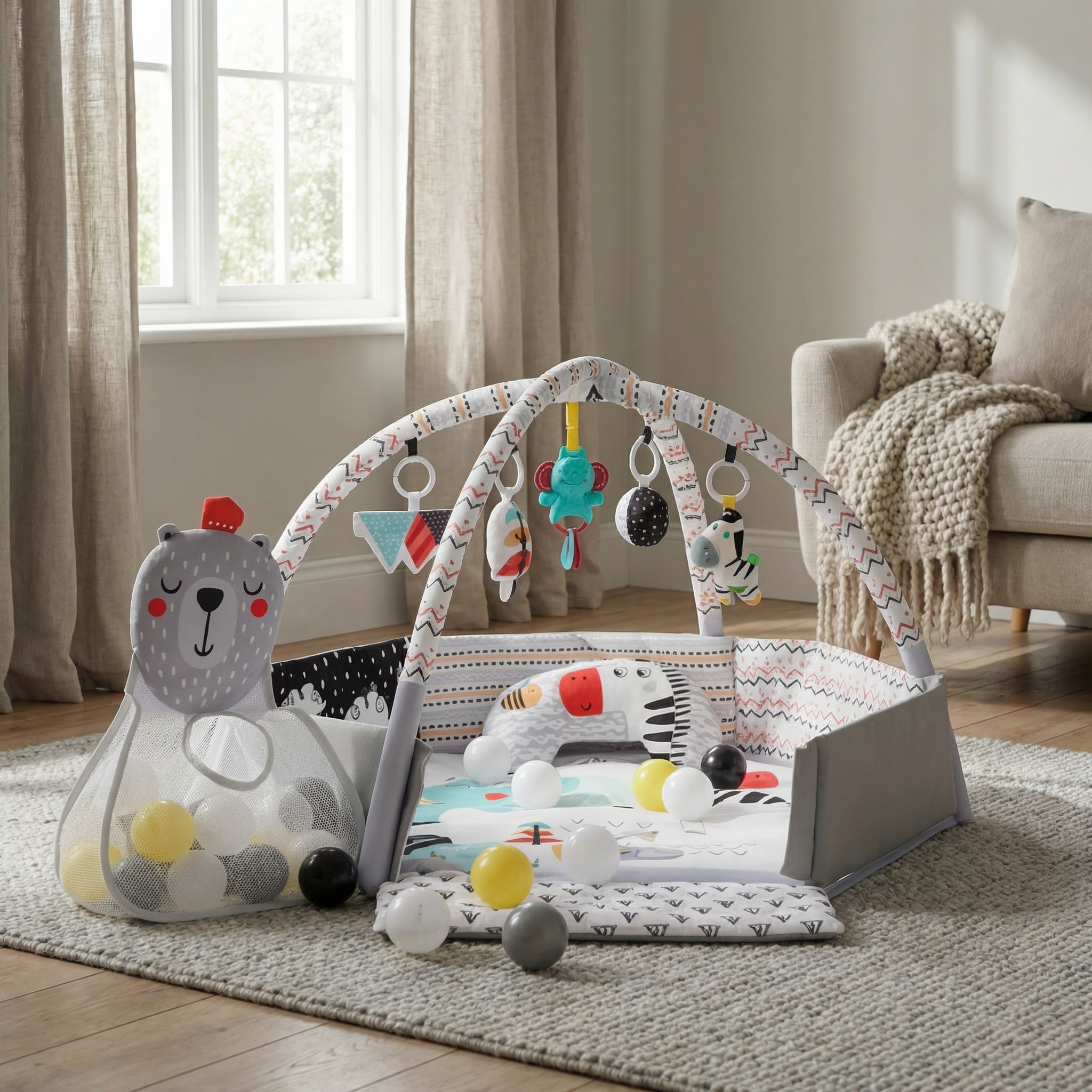 Grått og mønstret babygym og ballbinge med hengende leker og bjørneballoppbevaringspose.