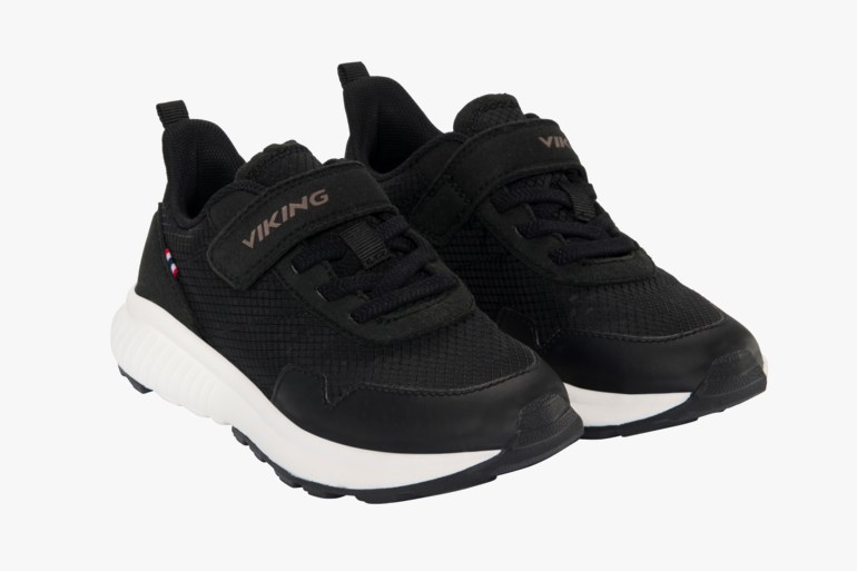 Et par svarte barnesko med hvite såler, overdel i mesh, elastiske lisser og svarte borrelåsremmer.