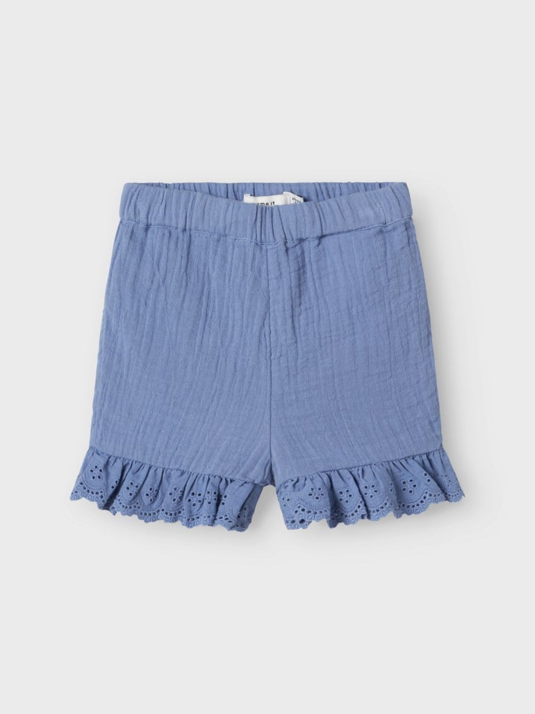 Blå krøllete shorts for barn med elastisk linning og rysjekant med broderte hull, forfra.