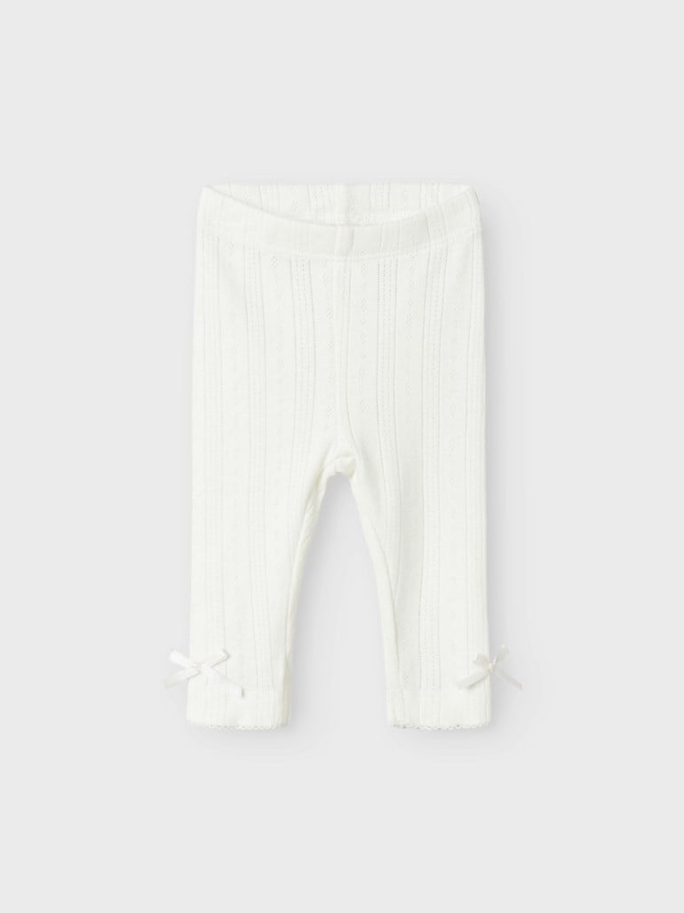 Hvite baby leggings med strikket mønster og små sløyfer ved anklene, forfra.