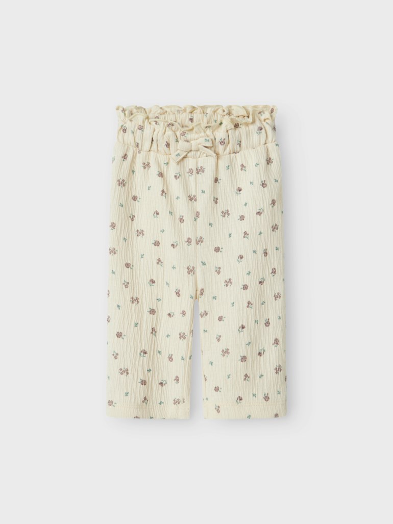 Off-white krøllet muslin babybukse med blomstertrykk, elastisk paper-bag midje og dekorativ sløyfe.