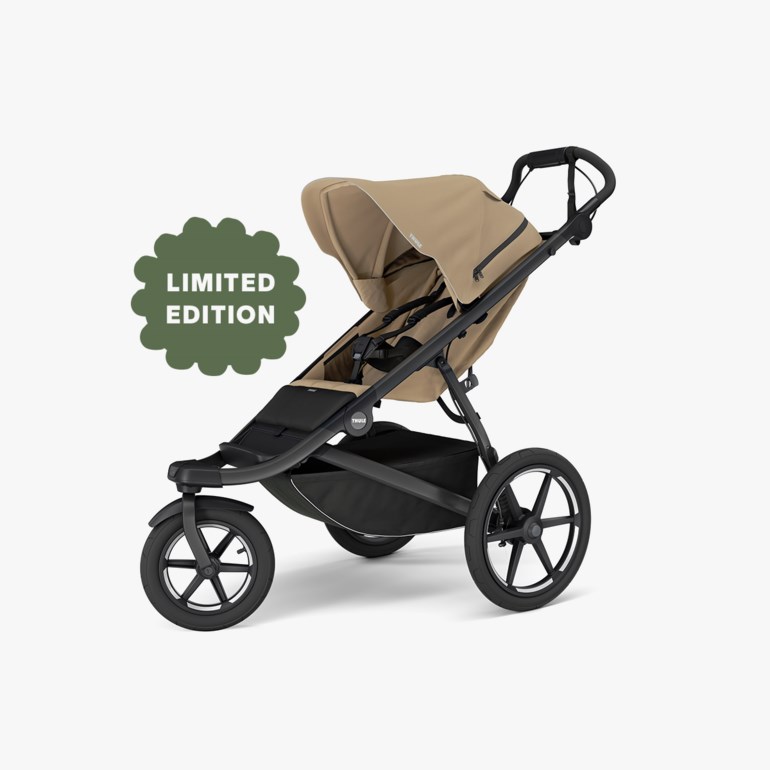 Beige og svart trehjulet joggevogn med solskjerm og oppbevaringskurv under setet.
