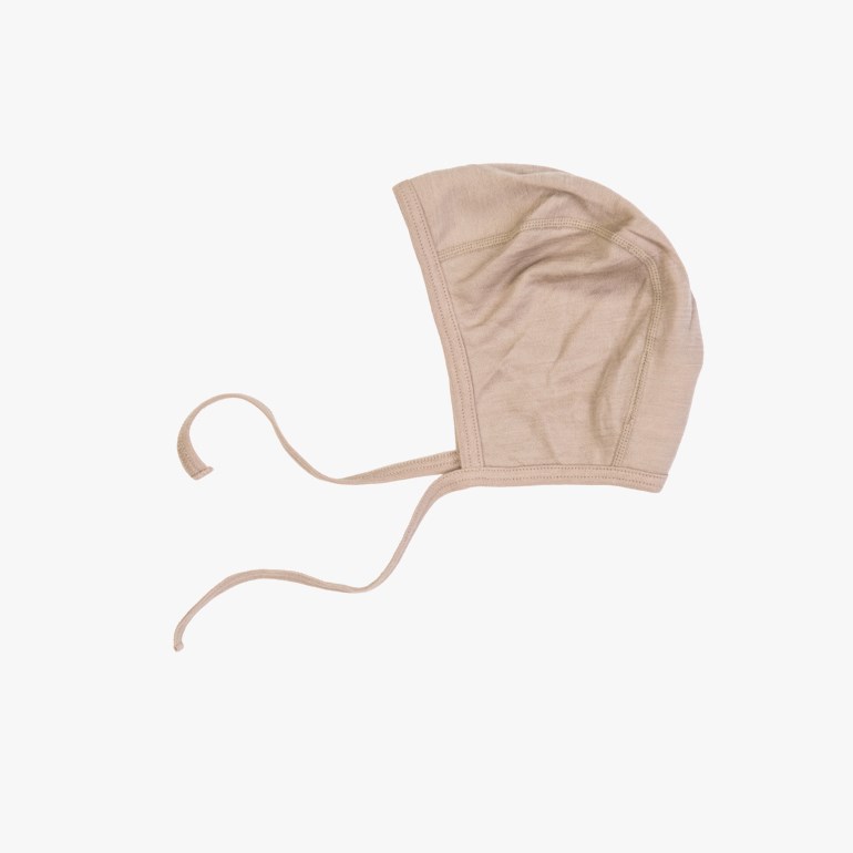 En beige strikket babylue med knytebånd, vinklet forfra.