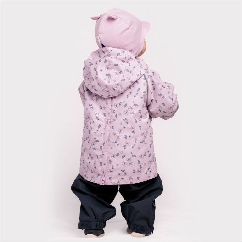 Baby bakfra i rosa mønstret jakke med hette, rosa ørelue og mørkeblå bukser.