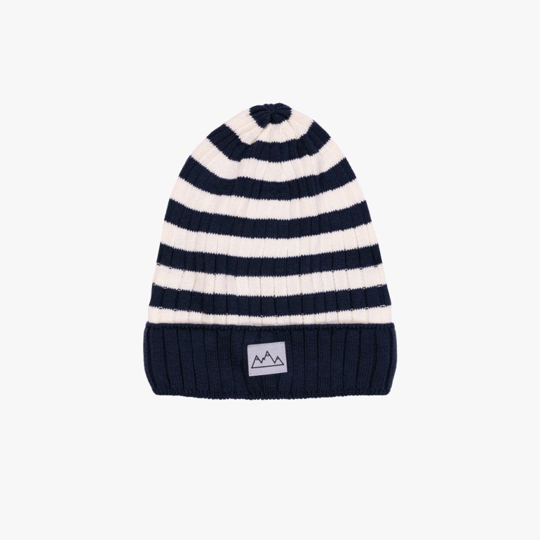 En ribbestrikket stripete lue i marineblått og kremhvit med en liten hvit fjell-logo merkelapp foran.