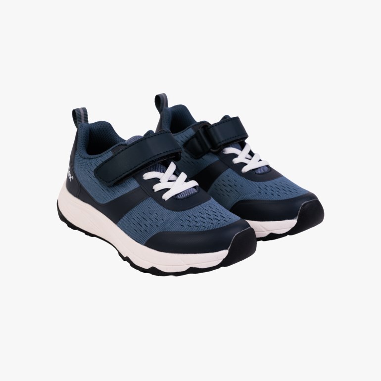 Et par mørkeblå og marineblå joggesko for barn med hvite såler, elastiske lisser og borrelås, sidevisning.