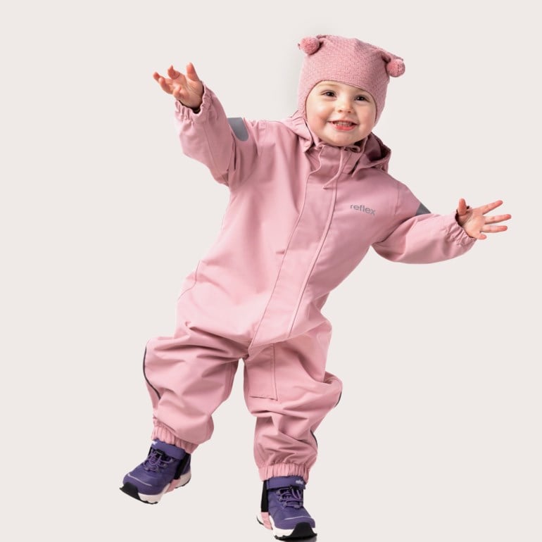 Barn har på seg en rosa hetteoverall med refleksdetaljer, en rosa strikkelue og lilla støvler.
