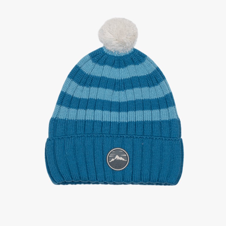 Blå og lyseblå stripet strikket lue med hvit dusk og fjellmotiv-merke.