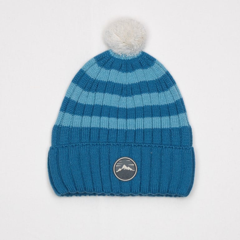Blå og lyseblå stripet strikket lue med hvit dusk og fjellmotiv-merke.
