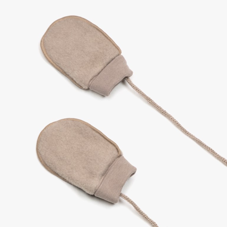 Et par beige babyvotter i filt med ribbestrikkede mansjetter, forbundet med flettet snor.
