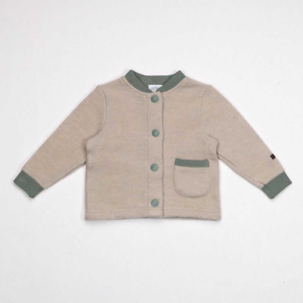 Barnejakke i beige med grønn kant, lange ermer, knapper foran og en lapplomme, forfra.