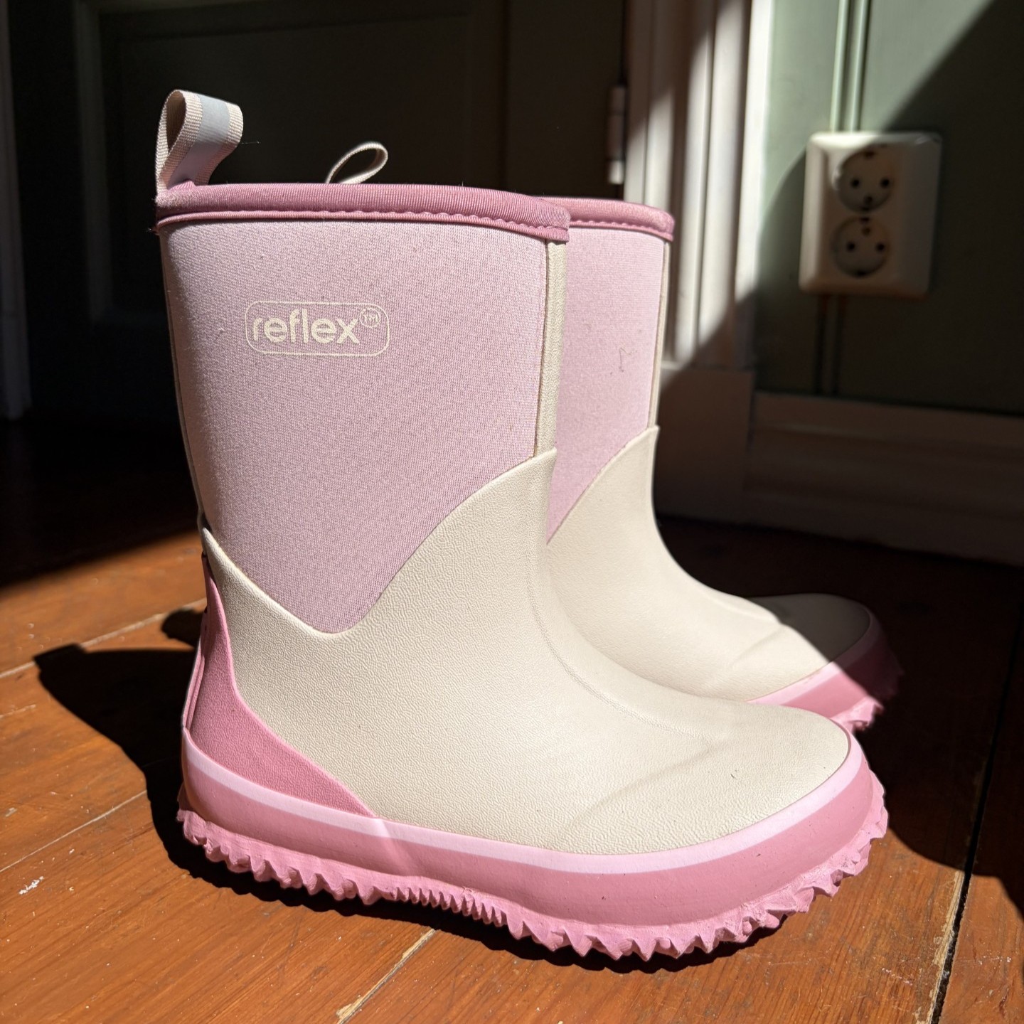 Et par rosa og off-white tofargede gummistøvler for barn med riflet såle.