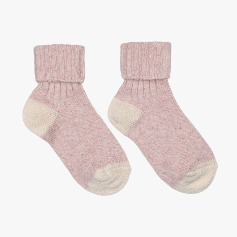 To strikkede rosa flekkete sokker med kremfargede ribbestrikkede mansjetter, hæler og tær.