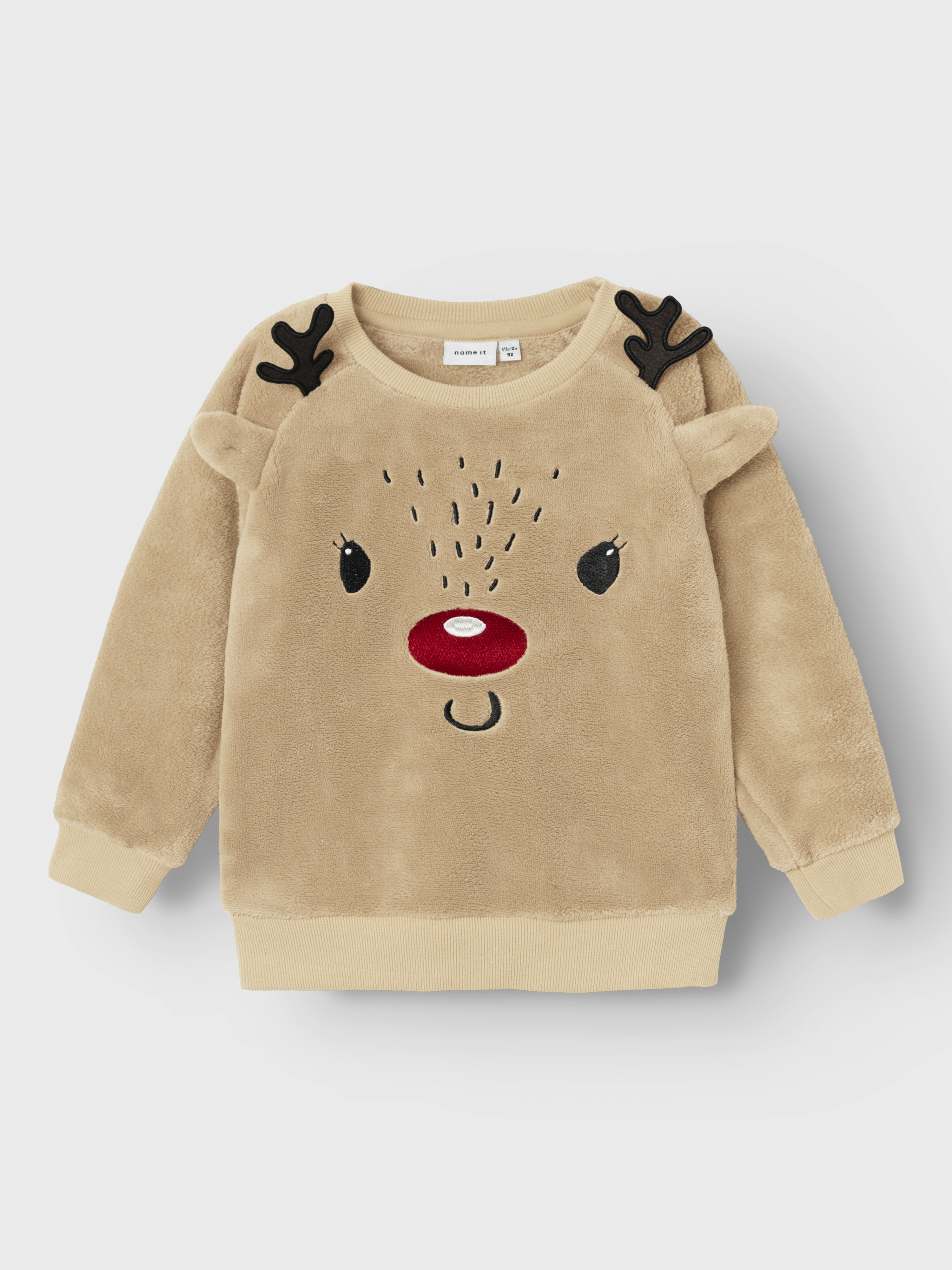 Barne beige fleecegenser med reinsdyrdesign, svarte gevirer, rød nese og ribbet kant.
