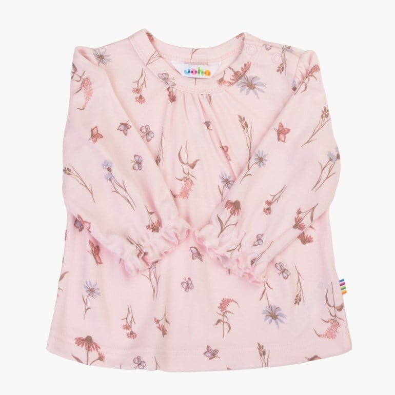 Rosa langermet babytopp med blomster- og sommerfugltrykk, rynket hals og volangermer, brettet forfra.