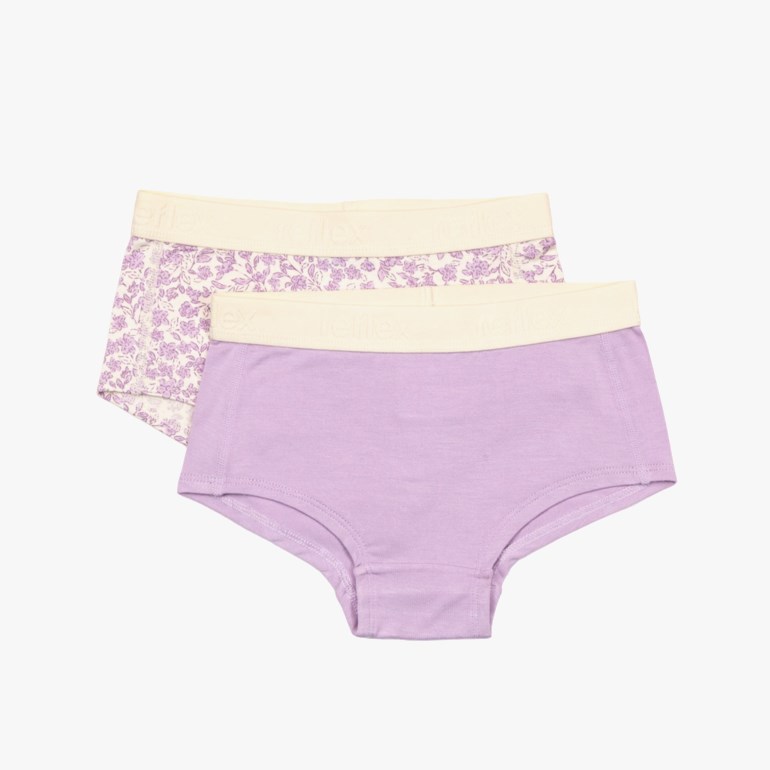 Lilla ensfargede barneundertøy med beige midjebånd, over hvitt blomstermønstret barneundertøy med beige midjebånd.
