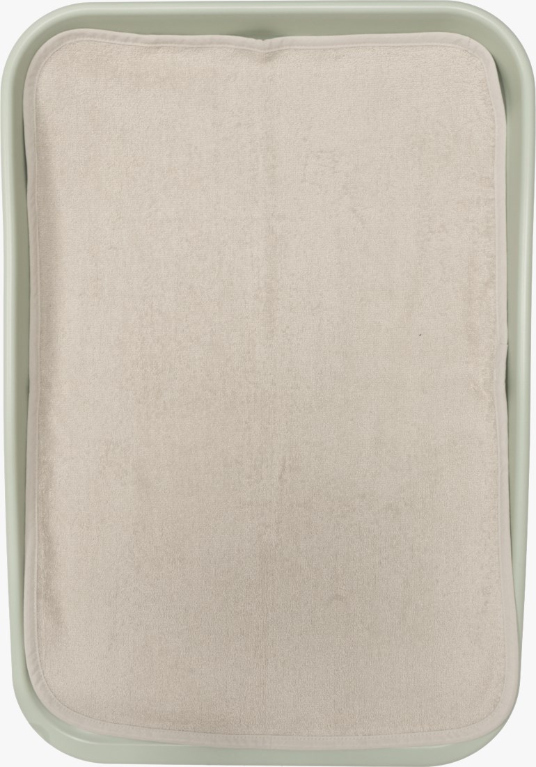 Beige rektangulært frottétrekk med avrundede hjørner i et lysegrønt brett.