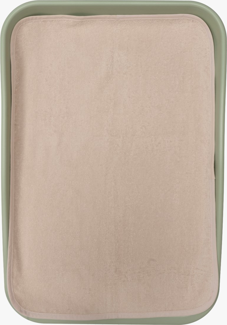 Lys rosa rektangulær stellemattepute med avrundede hjørner i en lys grønn stellemattebakke.