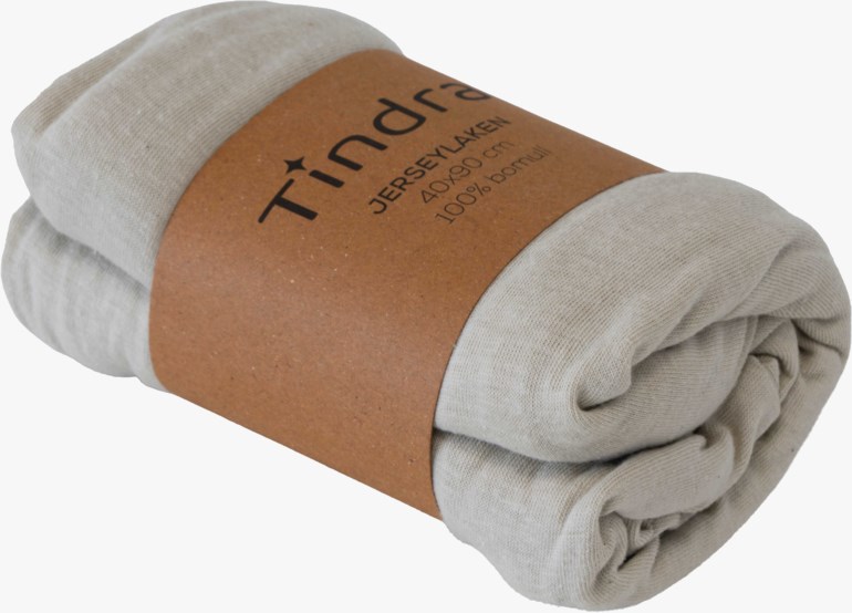 Et rullet lys beige jerseylaken i bomull med et brunt papirbånd som viser produktinformasjon.