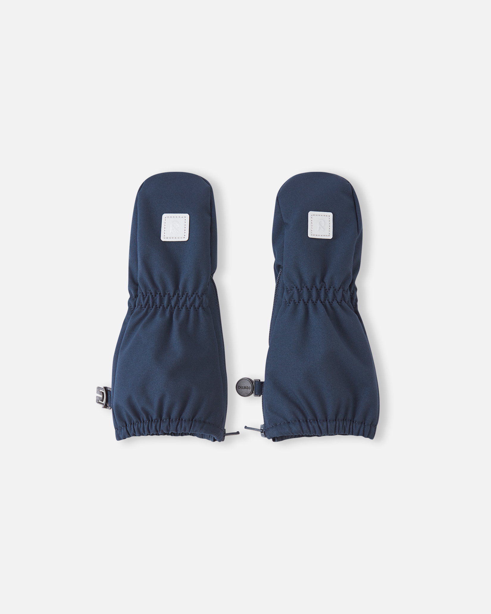 Et par mørkeblå barnevotter med elastiske håndledd og justerbare mansjetter, sett forfra.