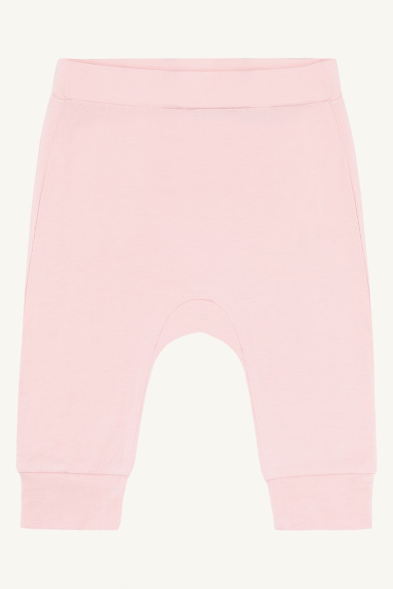 Frontvisning av rosa babyharemsbukser med bred elastisk linning og ribbestrikkede mansjetter.