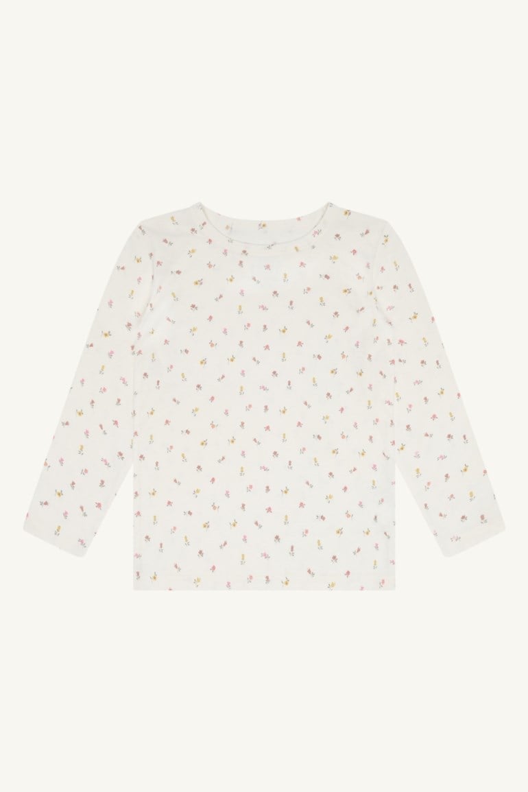 Hvit langermet barnetopp med lite rosa og gult blomstermønster, forfra.