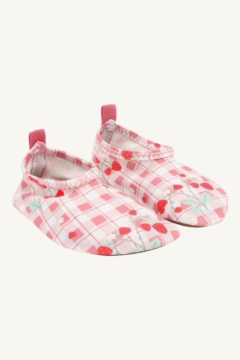 Et par barnrosa og hvitrutete badesko med jordbærmønster og rosa trekkstropper.