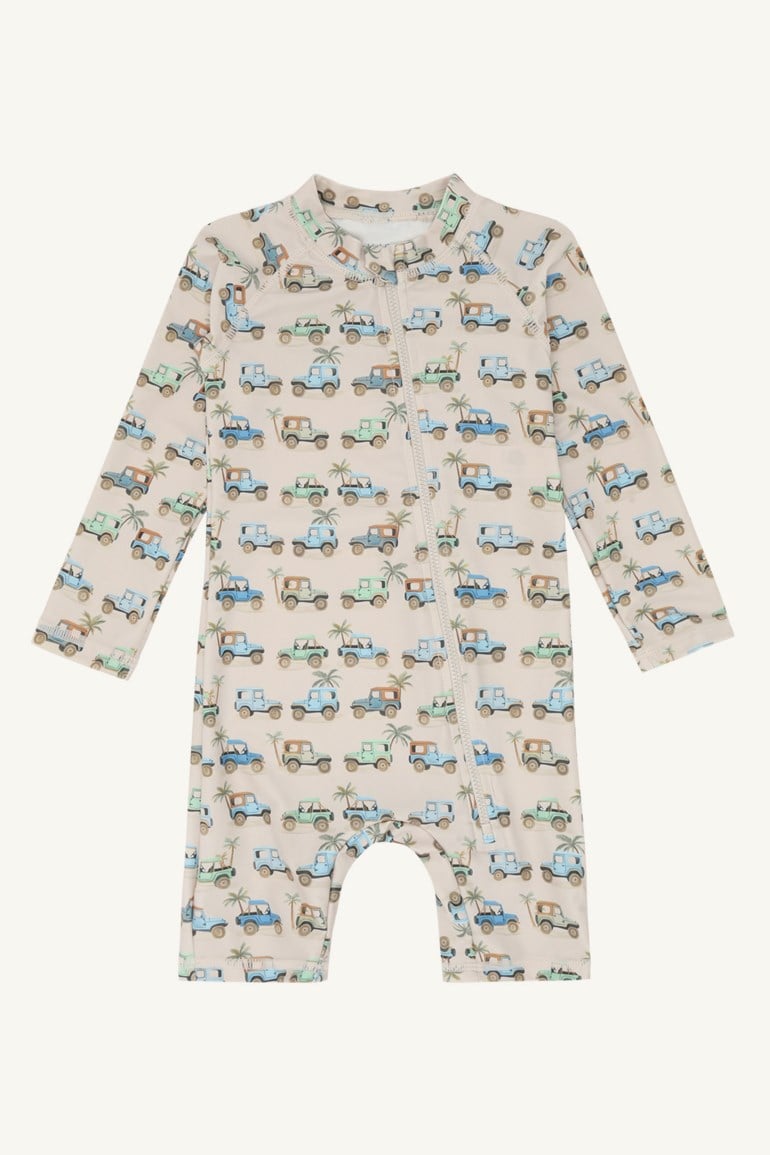 Frontvisning av en babys langermede lys beige UV-drakt med mønster av fargerike jeeper og palmer.