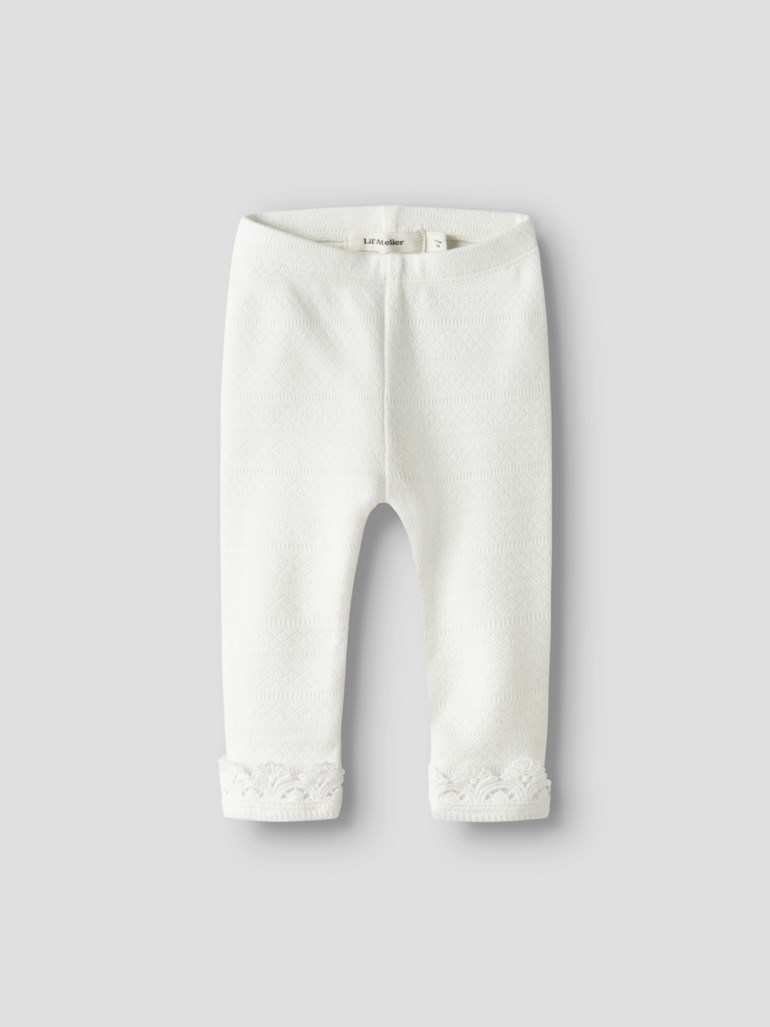 Hvite teksturerte strikkede baby leggings med subtilt diamantmønster og blondemansjetter, forfra.