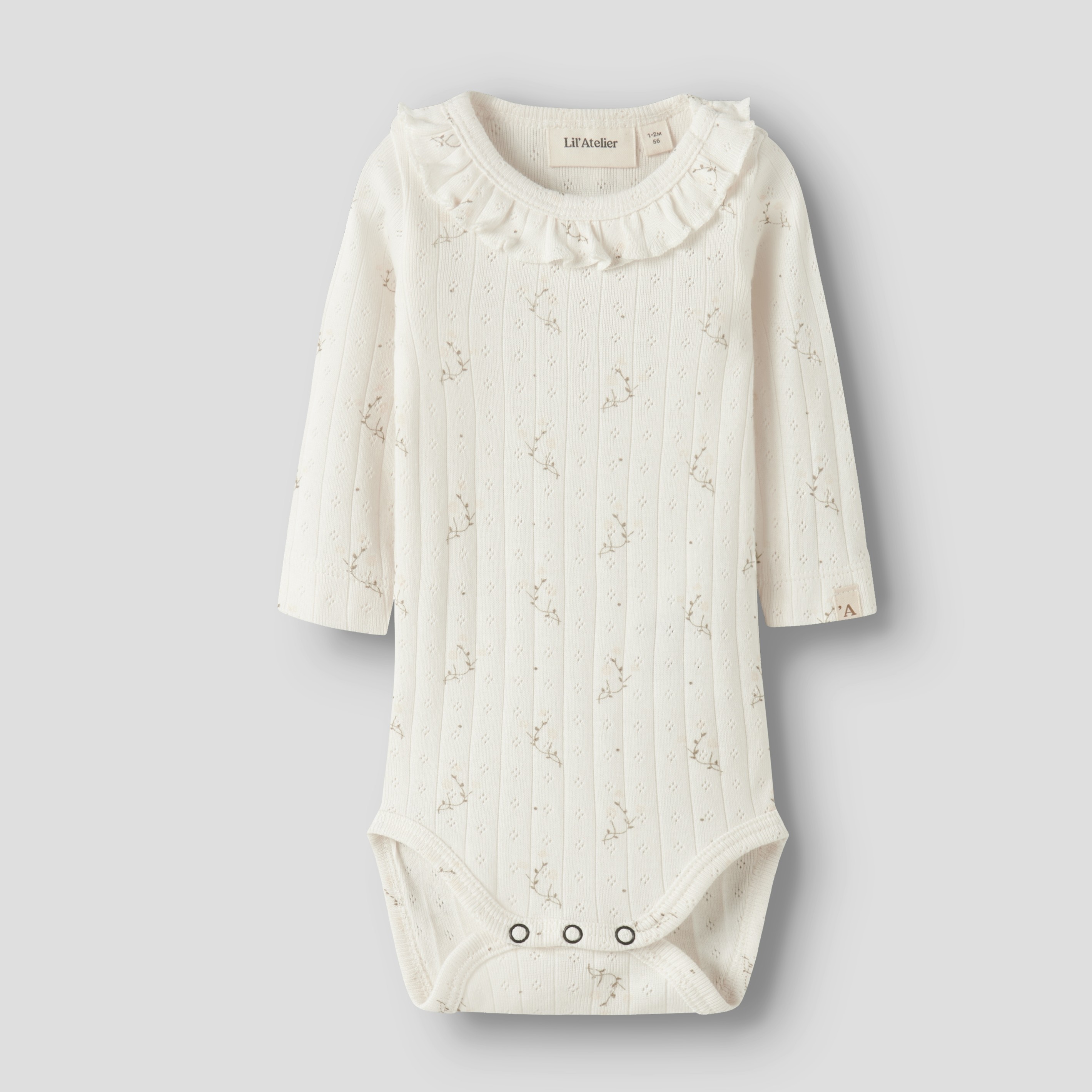 Frontvisning: Kremfarget babybody med lange ermer, volangkrave, diskret blomstermønster og trykknapper.